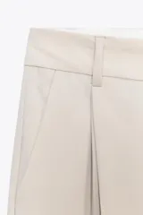 Pantalón marrón de tiro alto con trabillas, doble pliegue, bolsillos laterales y de vivo en la espalda, pernera ancha y cierre frontal con cremallera y gancho metálico.