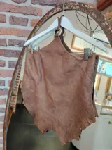 Top de cuero marrón con diseño artesanal, ajuste regulable con cordones en la espalda y detalle de argolla metálica.