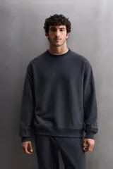 Sudadera de entrenamiento color gris claro, de corte relaxed fit, confeccionada en tejido de algodón con interior de rizo. Tiene cuello redondo, manga larga y acabados en rib.