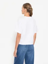 Remera blanca de algodón pima con estampado de la palabra "Love" en negro y tres flores rojas.