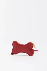 Monedero pequeño con forma de hueso, color gris claro, con cierre de cremallera dorada y correa de mano a juego. Presenta el logo de la marca estampado en dorado en el centro.