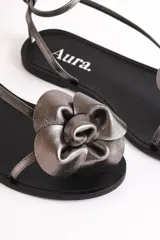 Sandalias bajas de cuero color suela, con tiras finas y aplique de flor roja en el empeine.