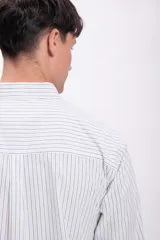 Camisa blanca a rayas verticales azules, de manga larga y corte clásico.