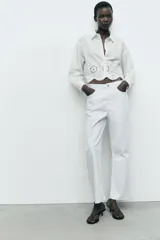 Camisa blanca corta de cuello solapa y manga larga. Bajo con bordados perforados combinados a tono. Cierre frontal con botones.