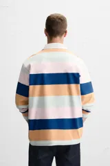 Polo de manga larga con cuello clásico y cierre de botones oculto. Diseño a rayas horizontales en colores azul, naranja, rosa y verde.