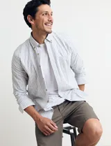 Camisa sport de algodón con cuello button-down y manga larga. Diseño a rayas verticales en tonos gris y blanco. Cierre frontal con botones de madera.