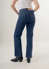 Pantalón de jean azul oscuro, de corte recto y tiro alto, con bolsillos delanteros y traseros. Presenta costuras verticales en el frente.