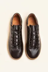 Zapatilla de cuero vacuno color azul marino, con cordones azules y suela de caucho color caramelo.