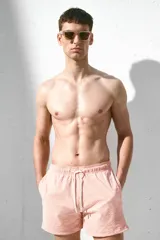 Short de baño color rosa con textura de sirsaca, elástico y cordón ajustable en la cintura, bolsillos laterales, bolsillo trasero ribeteado, aberturas laterales cortas y suspensor interior de malla.