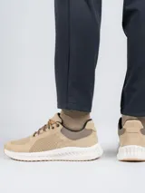 Zapatilla acordonada de cuero color beige con perforaciones en los laterales y suela blanca con base de goma color caramelo.