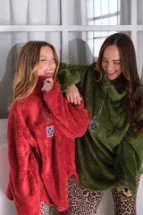 Buzo verde de peluche corderito con cierre parcial en el cuello y logo cuadrado en el pecho.