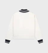 Cárdigan con cremallera color crema, con cuello y puños acanalados en azul marino. Logotipo bordado en el pecho.