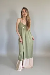 Vestido largo verde oliva con breteles finos y corte amplio. Tiene un ruedo en color beige.