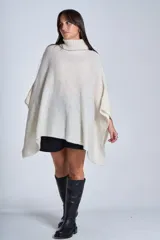 Poncho polerón tejido color crudo, con cuello alto y diseño holgado.