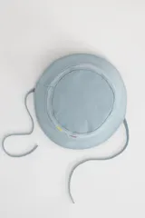 Gorro tipo bucket celeste con bordado de flores en el frente y tiras para atar debajo del mentón.