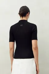 Top de manga corta color blanco, tejido con textura acanalada, cuello alto y terminaciones onduladas en mangas y ruedo.