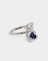 Anillo plateado con forma de oso y piedra azul en el centro.