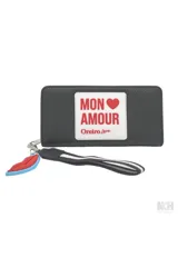 Billetera negra con aplique rectangular blanco con la frase "Mon Amour" en rojo y detalle de labios rojos y azules colgando del cierre.