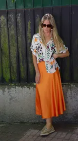 Falda midi evasé de raso color negro, con cintura elástica y cinturón con apliques metálicos.