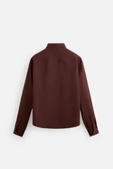 Camisa color borgoña de corte relajado, confeccionada en tejido con mezcla de viscosa. Tiene cuello solapa, manga larga con puños abotonados, bolsillo de parche en el pecho y cierre frontal con botones.
