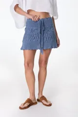 Minifalda tejida a crochet color ladrillo, con cintura alta y cordón trenzado con borlas.