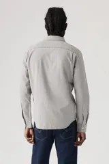 Camisa de chambray gris claro, de corte estándar, con cuello abotonado, manga larga, bolsillo de parche en el pecho y cierre frontal con botones.