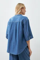 Camisa de jean celeste de corte recto, con cuello mao, mangas cortas y cierre frontal con botones.