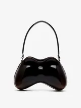 Bolso de hombro con forma orgánica tridimensional, inspirado en un control de videojuegos. Construcción rígida soft-touch, color negro brillante con detalles en marrón oscuro en los bordes. Posee un remache metálico ovalado en el frente y correa fija al hombro.