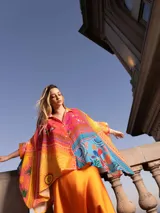 Poncho estampado con diseño abstracto en tonos naranja, amarillo, rosa y celeste, con mangas cortas.