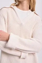 Buzo de punto color crudo con cuello polo y aberturas laterales.