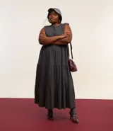 Vestido midi gris sin mangas, con cuello redondo, corte recto y volados en la falda.