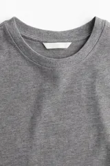 Remera gris de algodón, corte amplio, con mangas cortas y cuello redondo.