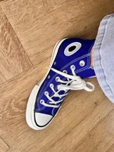 Zapatillas de lona blancas de caña alta con cordones y puntera de goma. Logo de durazno engomado en la base y en la cara interna.