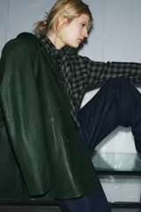 Blazer de piel color verde oscuro, de corte cruzado con doble botonadura negra, cuello solapa de muescas y manga larga.