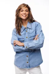 Sobrecamisa celeste de jean con cuello camisero, cierre frontal con botones dorados, dos bolsillos con solapa en el pecho y mangas largas con puños abotonados.