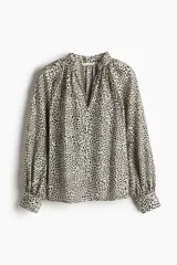 Blusa oversized con cuello elevado fruncido, abertura en V adelante y bajo recto. Mangas globo largas de corte raglán con abertura y botón en los puños.