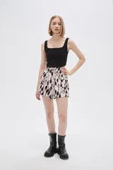 Short de poliéster con estampado abstracto en tonos beige, negro y gris. Tiene bolsillos delanteros con solapa y botón, y es de calce alto.
