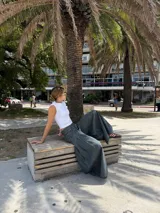 Pantalón de jean ancho, color verde oscuro o gris verdoso, de tiro alto con pliegues frontales y corte extremadamente holgado.