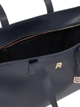 Cartera tipo tote estructurada de color azul marino, confeccionada en poliuretano con forro de poliéster. Presenta asas de hombro dobles, un bolsillo interior con cremallera, un monograma TH metálico en el frente y un charm colgante desmontable con el logo TH.