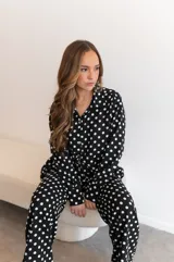 Camisa negra con estampado de lunares blancos, de manga larga y cuello clásico.