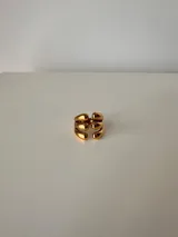 Anillo dorado con diseño de tres bandas horizontales paralelas, ajustable entre 16mm y 19mm. Fabricado en acero quirúrgico hipoalergénico.