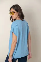 Blusa italiana color celeste con bordado de plumas al tono en el frente, confeccionada en lino y algodón.