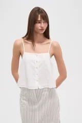 Musculosa blanca de algodón con breteles finos, bordado calado y botones frontales.