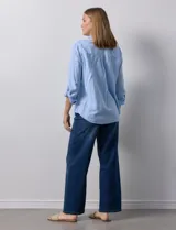 Camisa celeste de lino, con cuello con solapa, escote en V y abertura central con botones. Largo de manga regulable con presilla y botón. Delantera con bolsillo aplicado.