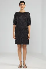 Vestido corto negro con brillos plateados, de tejido de punto con mangas 3/4 y corte recto.