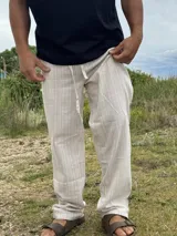 Pantalón de lino beige y crudo a rayas, de corte ancho y relajado.