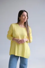 Sweater amarillo de corte recto con cuello redondo. La parte delantera es más corta que la trasera y tiene aberturas en la espalda.