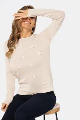 Buzo color beige de tejido de punto con bordado de pequeñas flores blancas.