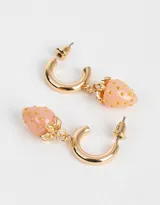 Aros dorados tipo argolla con dije colgante de frutilla color rosa y detalles dorados.