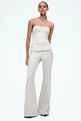 Top bustier de sarga color crudo, con escote strapless, copas acolchadas y costuras decorativas adelante y atrás. Tiene varillas delanteras para dar forma y aportar sujeción, y cierre visible en la espalda. Está forrado.